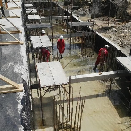 Multi‑disciplinary construction team reviewing concrete building plans with waterproofing membranes and ACP cladding.