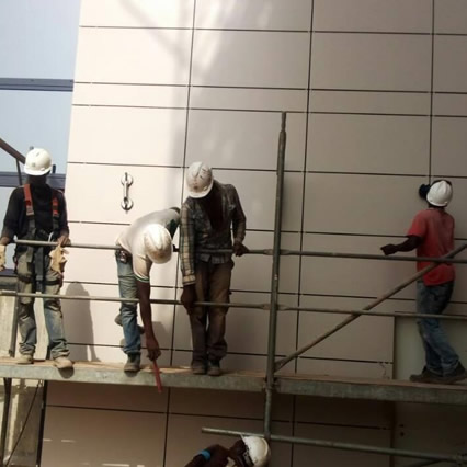 Multi‑disciplinary construction team reviewing concrete building plans with waterproofing membranes and ACP cladding.