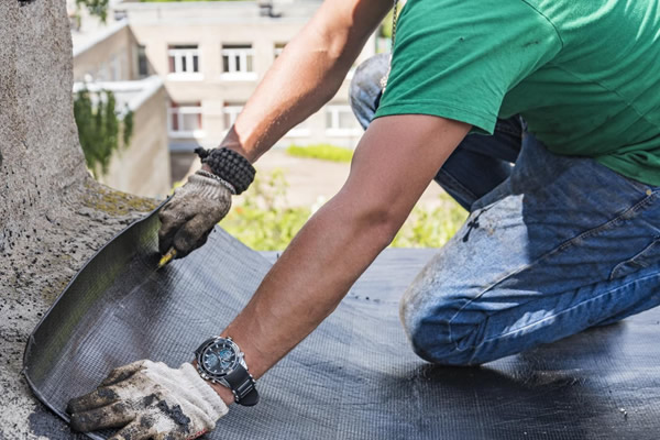 Technician applying damp-proofing membrane to prevent rising moisture in a residential building wall